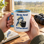 Hands holding the Birds First, Coffee Second mug next to binoculars and a field guide